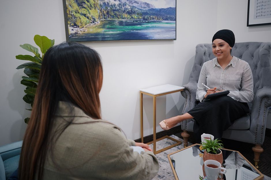 Two women in a cozy office setting engage in a friendly and casual meeting.